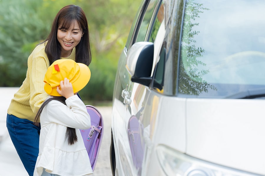 車に乗ろうとしている女の子と保護者